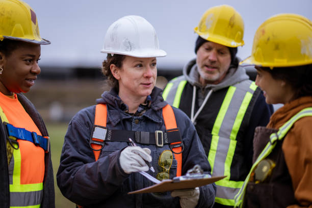 A small group of constructions workers huddle together as they take instructions from the site supervisor. They are each wearing proper protective gear and are listening attentively. how to choose the right architects and engineers