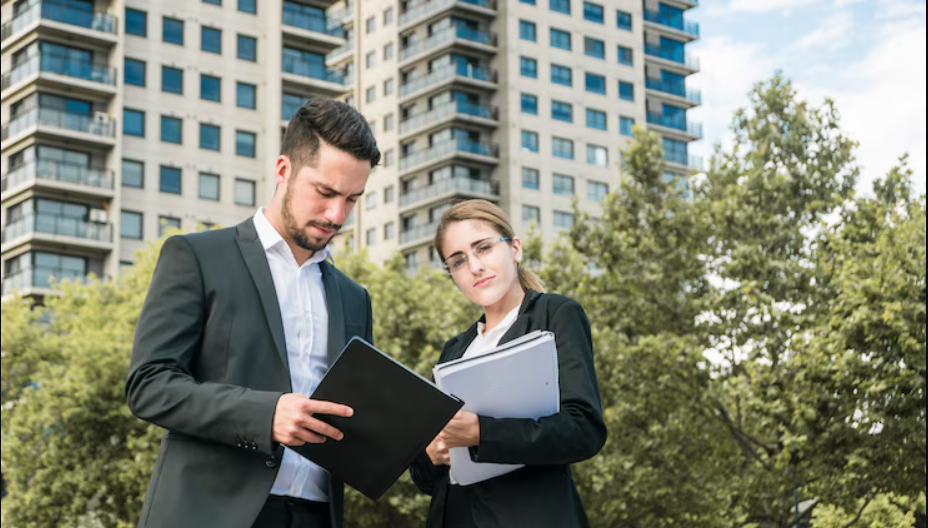 Close-up of businessman and businesswoman holding documents standing in front of building