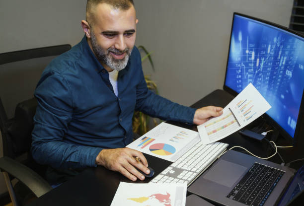 Businessman analyzing crypto currency market graphs on computer and laptop screen at home. Bitcoin / Cryptocurrency concept