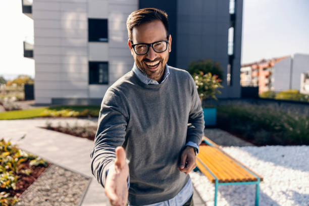 A real estate agent giving handshake in front of the property.