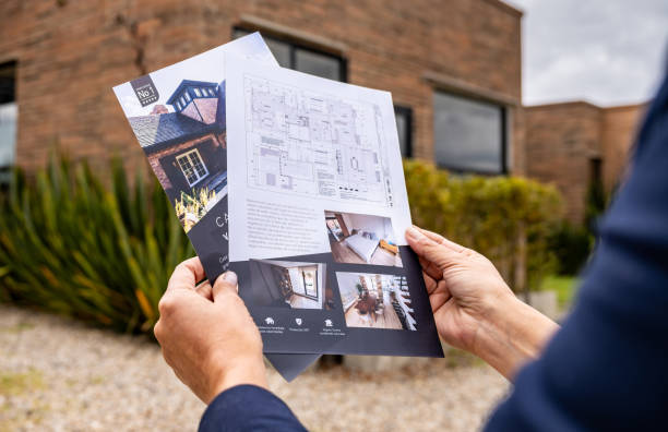 Close-up on a real estate agent holding brochures of a house for sale