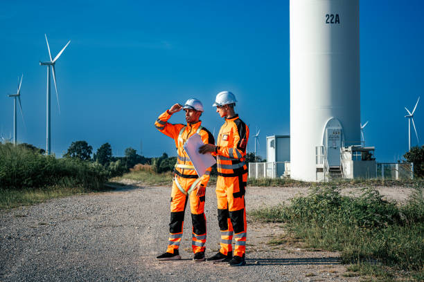 Two engineers are working at windmills field for generate electricity