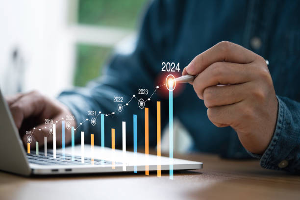 Businessman use electronic pen writing rising colorful graph from 2023 to 2024 year of business planing and stock investment growth concept. AB 2097 Parking