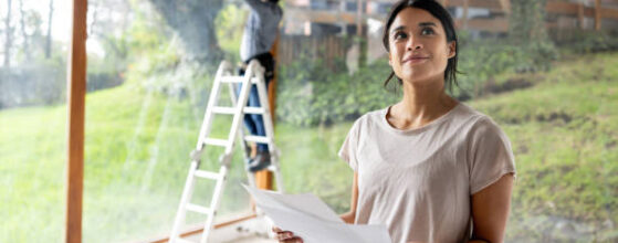 Latin American female architect renovating a house and holding designs at the construction site