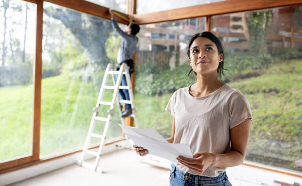 Latin American female architect renovating a house and holding designs at the construction site