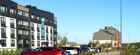 Cars on parking lot in residential complex near multi-story residential building. High multi-storey buildings. Cars on parking on Street with modern apartment buildings. Colourful facade of buildings.