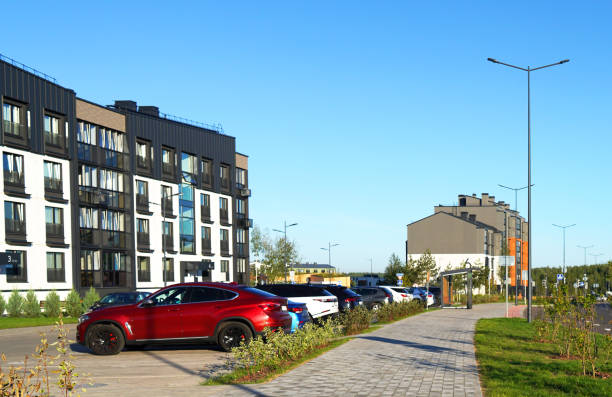 Cars on parking lot in residential complex near multi-story residential building. High multi-storey buildings. Cars on parking on Street with modern apartment buildings. Colourful facade of buildings.