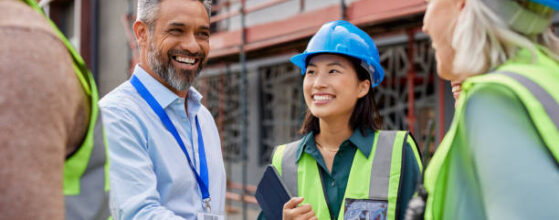 Smiling construction professionals exchanging a handshake as part of their partnership on site. Happy engineer shaking hands at construction site with happy businessman. Handshake between middle eastern construction manager with architect at building site, conclude an agreement.