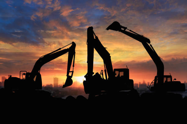 Crawler excavators silhouette are digging the soil in the construction site. on sunset background