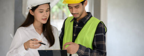 Female civil engineer with personal safety equipment check and consult with construction site foreman technician for inspect building construct process during follow up process. Engineering concept.