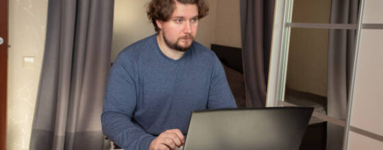 Man with laptop at home, study and internet-based job in a home office, modern digital tools for work.