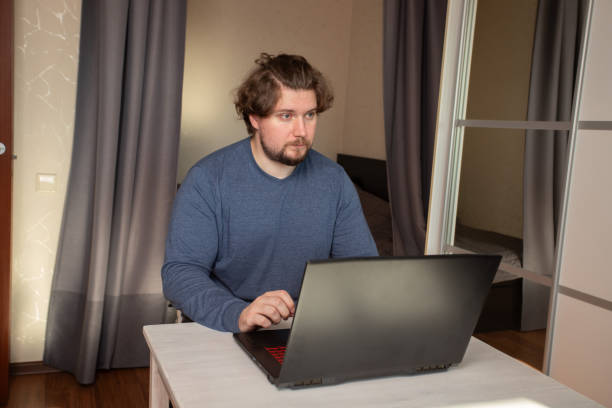 Man with laptop at home, study and internet-based job in a home office, modern digital tools for work.