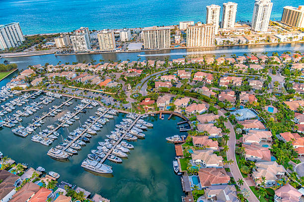 A marina along the canals within a residential community in Hollywood, Florida with high rise tourist resorts along the beach shot via helicopter from an altitude of about 1000 feet.
