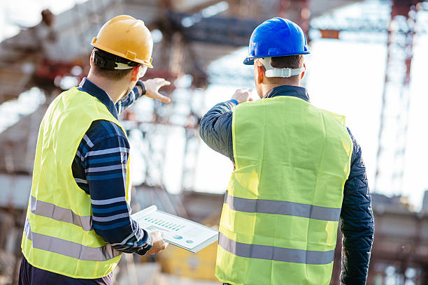 Two experts engineers in protective helmets and fluorescent vests showing the construction site and building activities after the successful project phase. Image taken with Nikon D800 and 85mm developed from RAW in XXXL size, in Novi Sad, Serbia, Central Europe, Europe