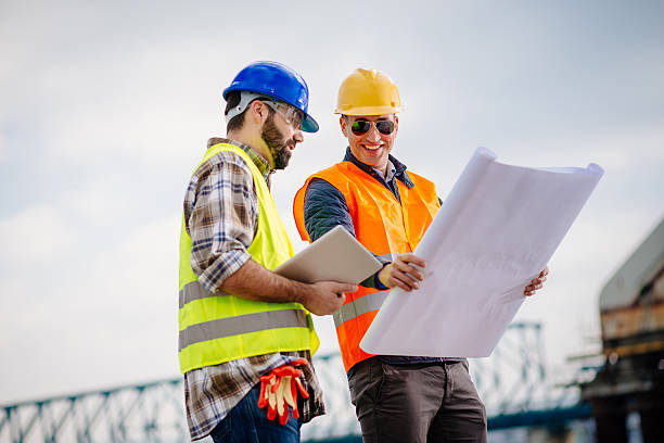 Two experts engineers in protective helmets and fluorescent vests showing the construction site and building activities after the successful project phase. Image taken with Nikon D800 and 85mm developed from RAW in XXXL size, in Novi Sad, Serbia, Central Europe, Europe
