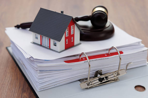 Close-up of a court gavel and a miniature house on a stack of documents