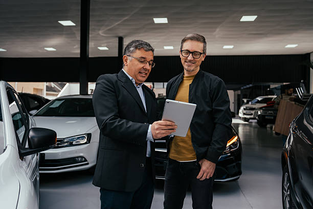 Car salesman talking to customer at dealership