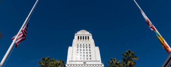 Los Angeles City Hall, tall historic building framed by flag poles, March 2, 2017, Los Angeles, California, USA