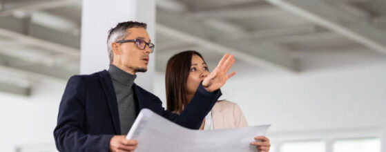 Businesspeople Meeting To Look At Plans In Empty Office