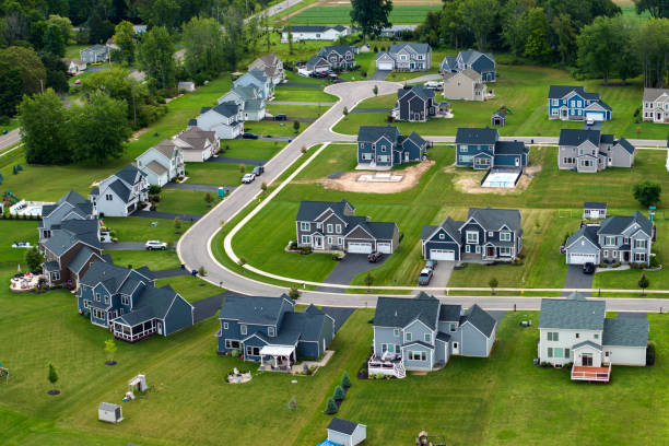 Low-density two story private homes in rural residential suburbs outside of Rochester, New York. Upscale suburban houses with large lot size and green grassy lawns in summer season.