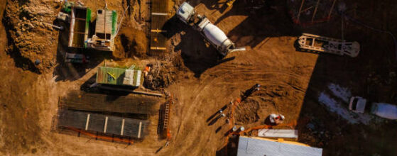 Top aerial view of a construction site with cement mixer truck, machinery and workers