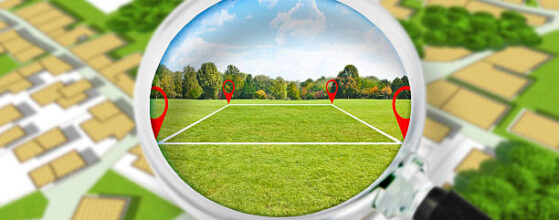 Land management with an imaginary cadastral map of territory with a vacant land available for sale or building construction - Concept seen through a magnifying glass